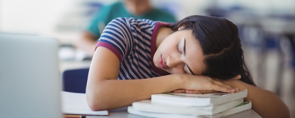 Vrouw slaapt op boeken omdat ze geen energie heeft